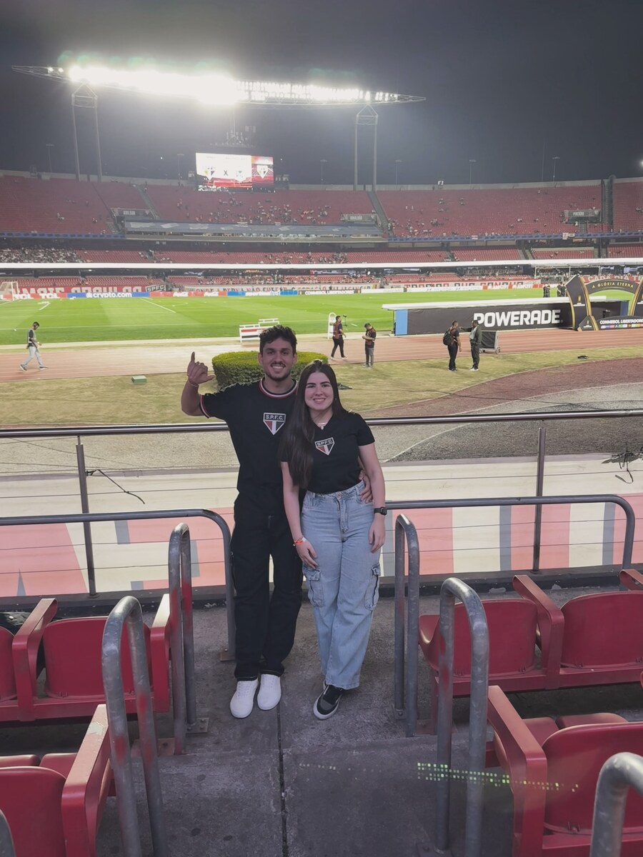 João e Mel num estádio de futebol.