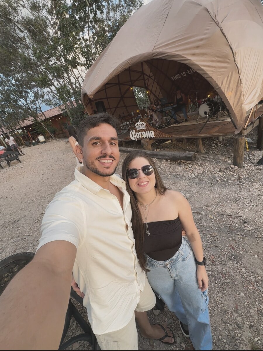 João e Mel numa viagem, ao lado de uma barraca de camping.